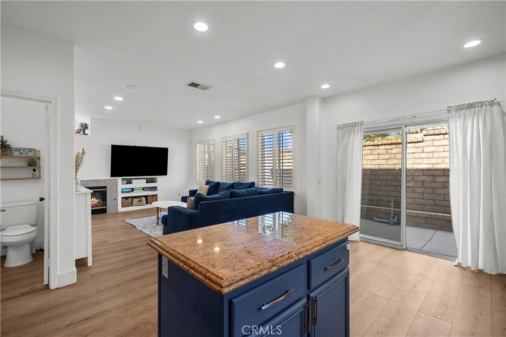 Open-plan kitchen and living room with a stone-topped blue island and sliding doors to a walled patio.