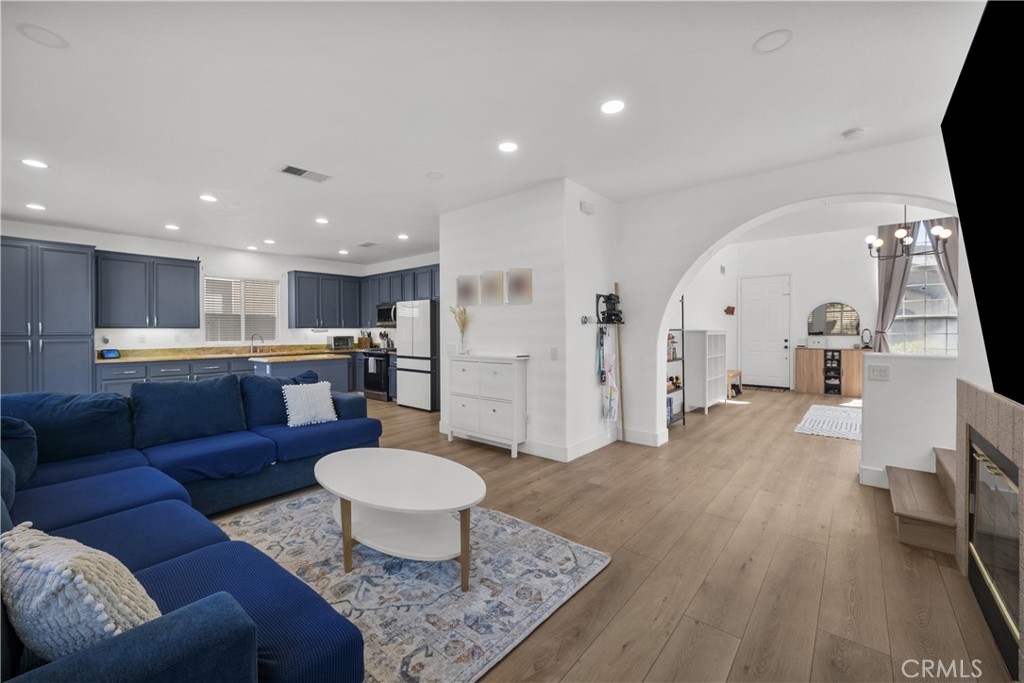 Open living room with blue sectional and kitchen, connected to an adjoining room through an archway.