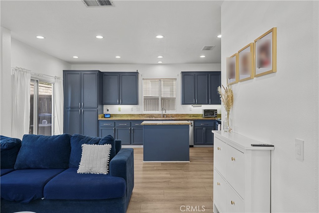 Open kitchen and living area with navy cabinets, a central island, and a blue sofa.