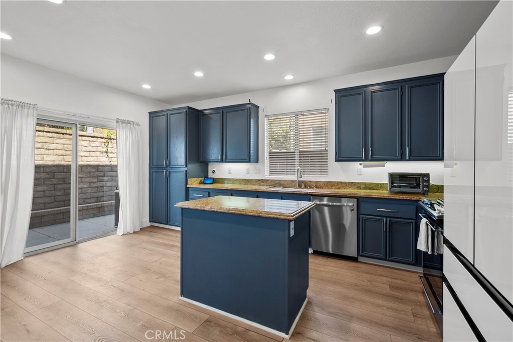 Kitchen with navy cabinets, granite island, stainless steel appliances, and sliding glass doors to a patio.