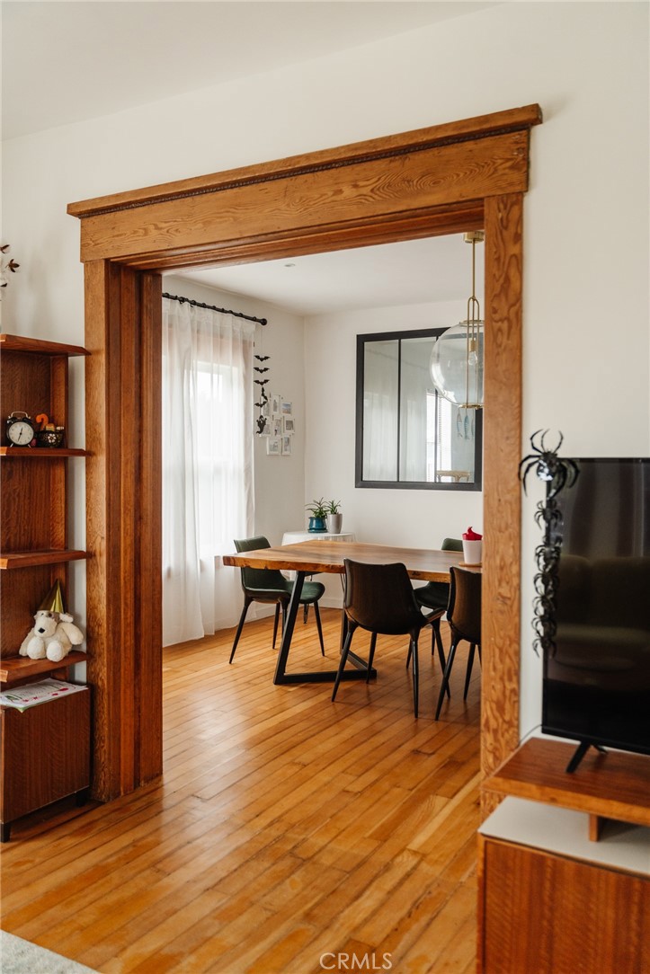 Dining room with hardwood floors, a dining table, and a wide wood-trimmed opening.