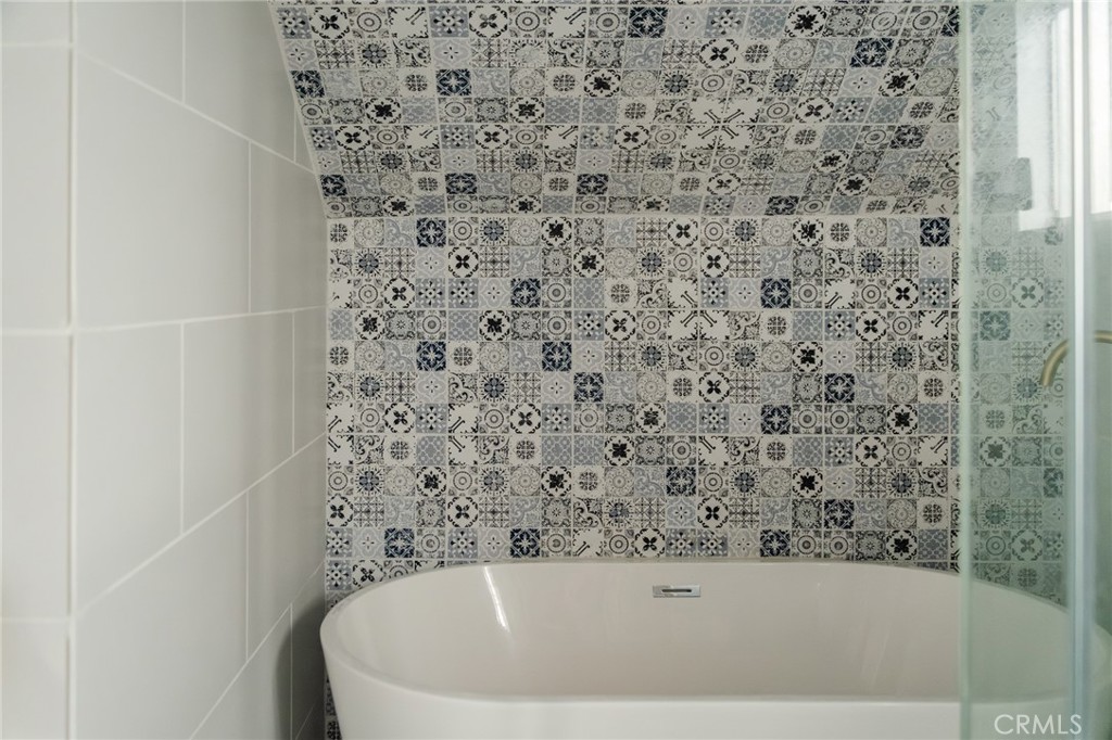 Bathroom with a white bathtub and patterned tile walls and ceiling.