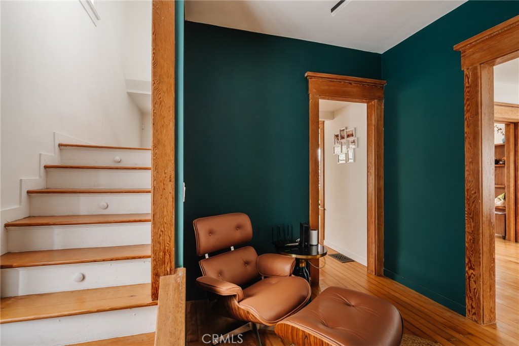 Furnished room with teal walls, a white staircase, and a brown leather lounge chair and ottoman.