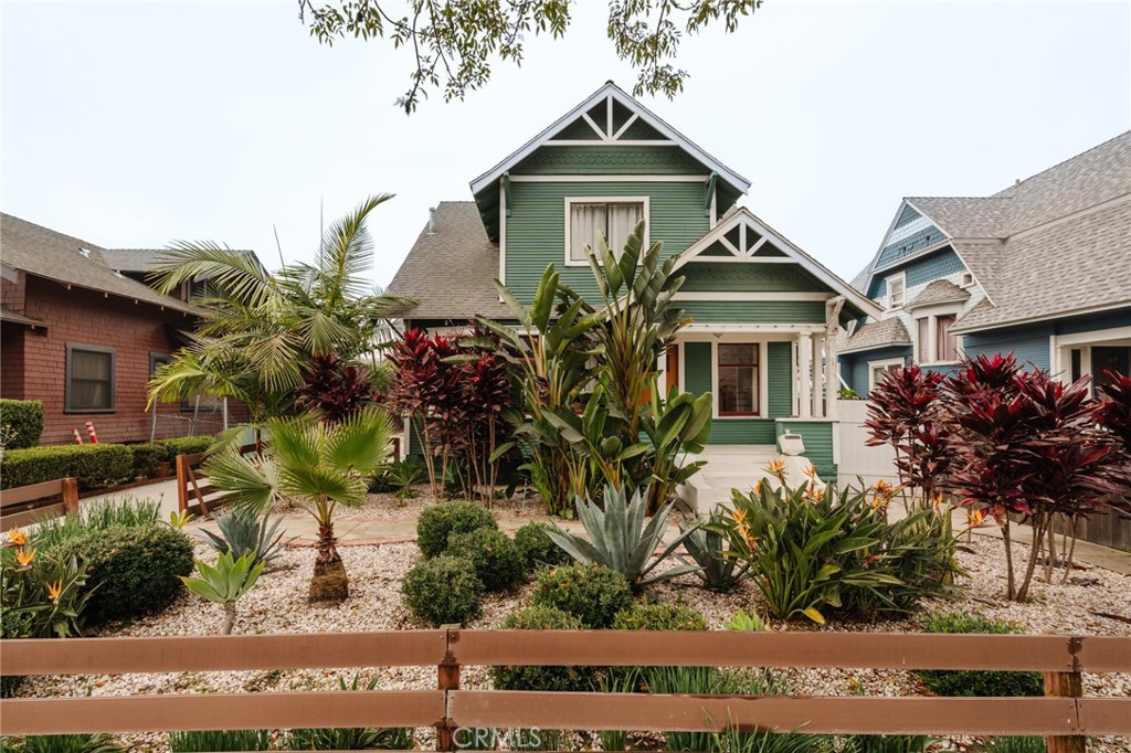 Green Craftsman-style house with white trim, decorative gables, and a landscaped front garden.