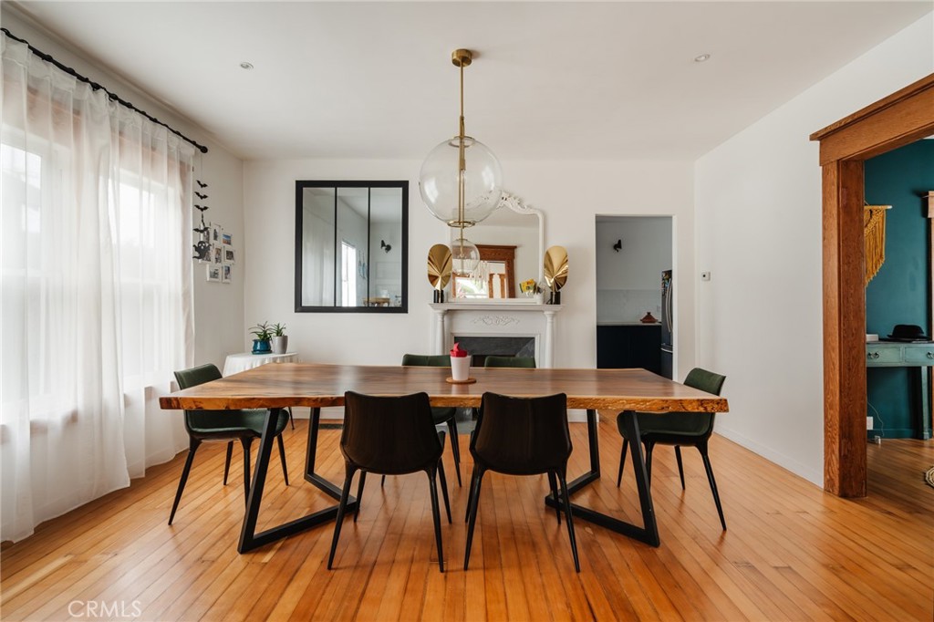 Dining room with a long wooden table, black chairs, hardwood floors, and a white fireplace.