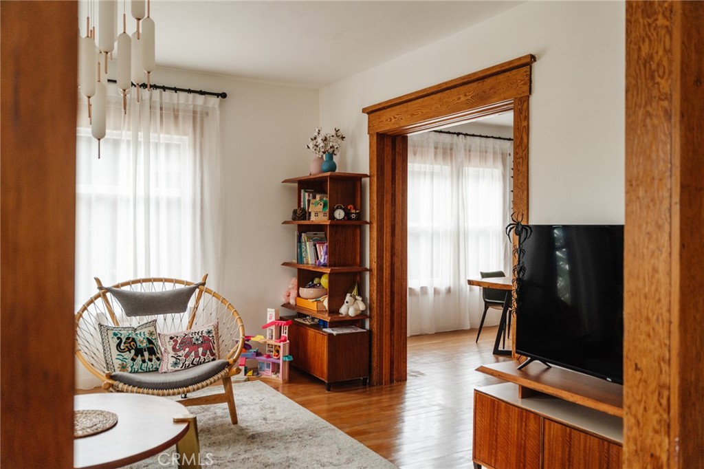 Living room with hardwood floors, carved wood trim, a rattan chair, and television