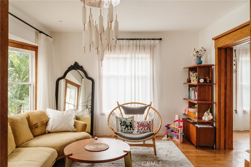 Living room with a mustard sectional, wicker chair, ornate mirror, and warm wood trim.