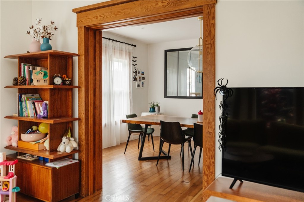 Dining area framed by a wide wooden doorway, with hardwood floors and a modern table.