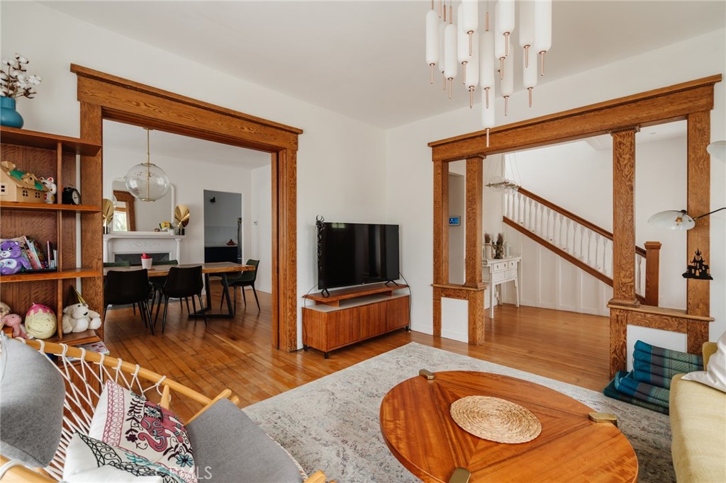 Living room with ornate wood-trimmed openings, hardwood floors, and an adjoining dining area.