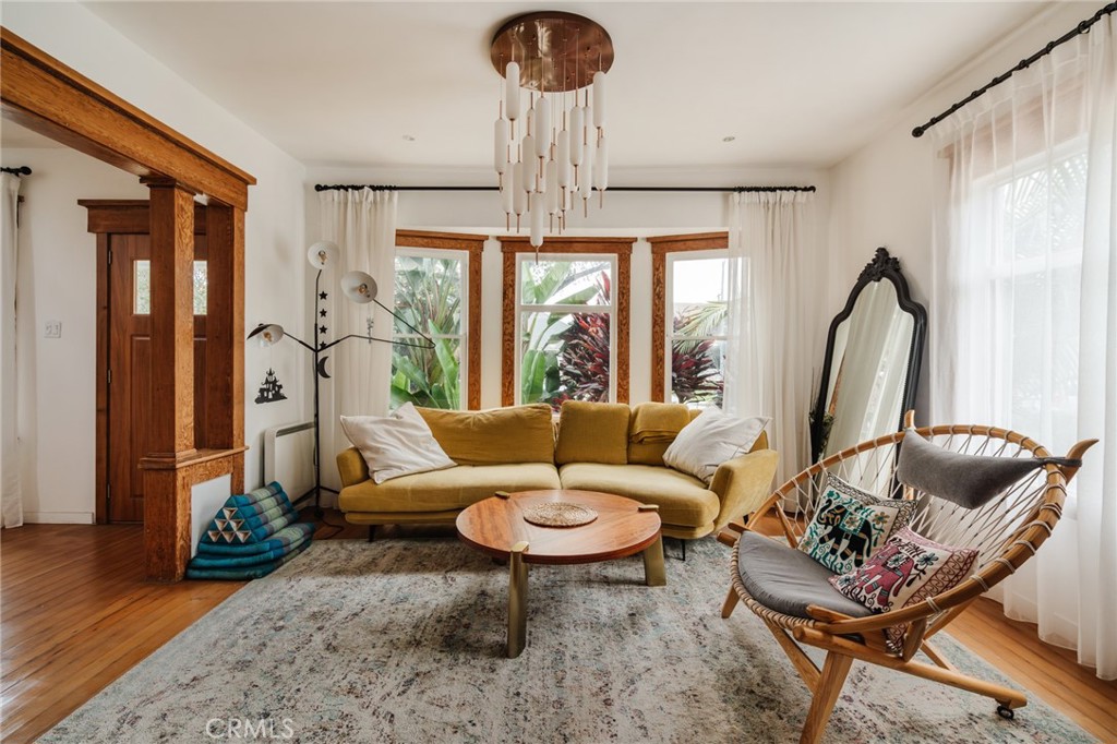 Living room with a mustard-yellow sectional, tropical garden views, and ornate wood trim.