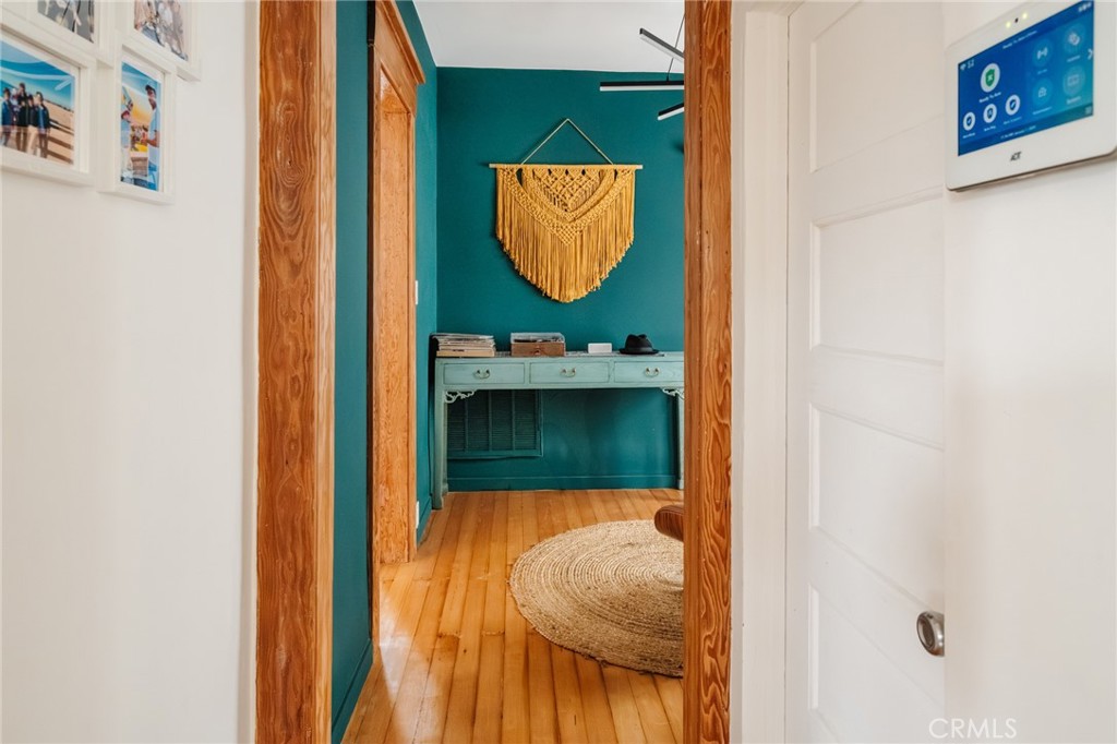 Wood-trimmed hallway opens to a teal entry room with hardwood floors and a console table.