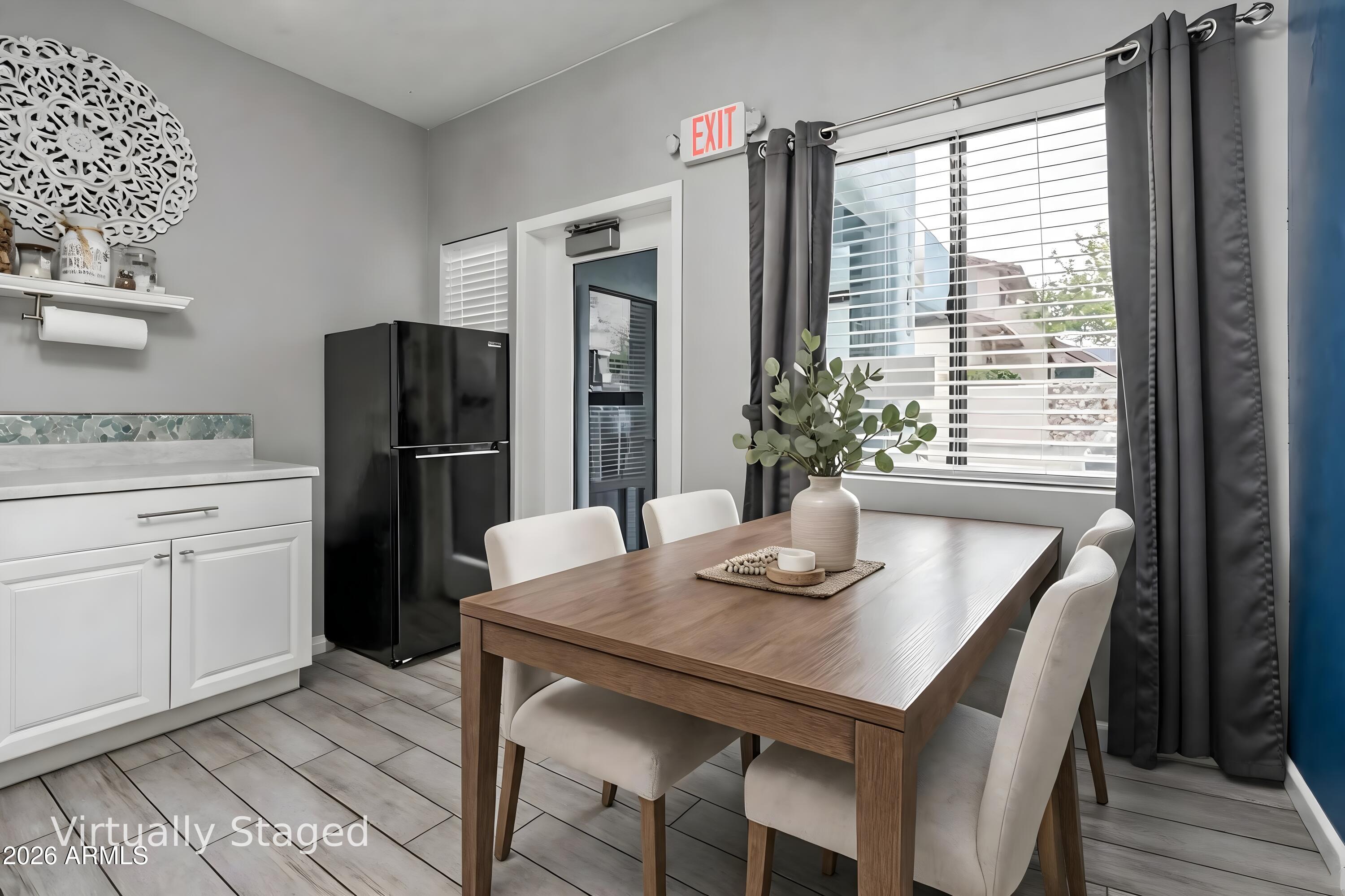 Virtually staged dining area with a wooden table, white chairs, and a large curtained window.
