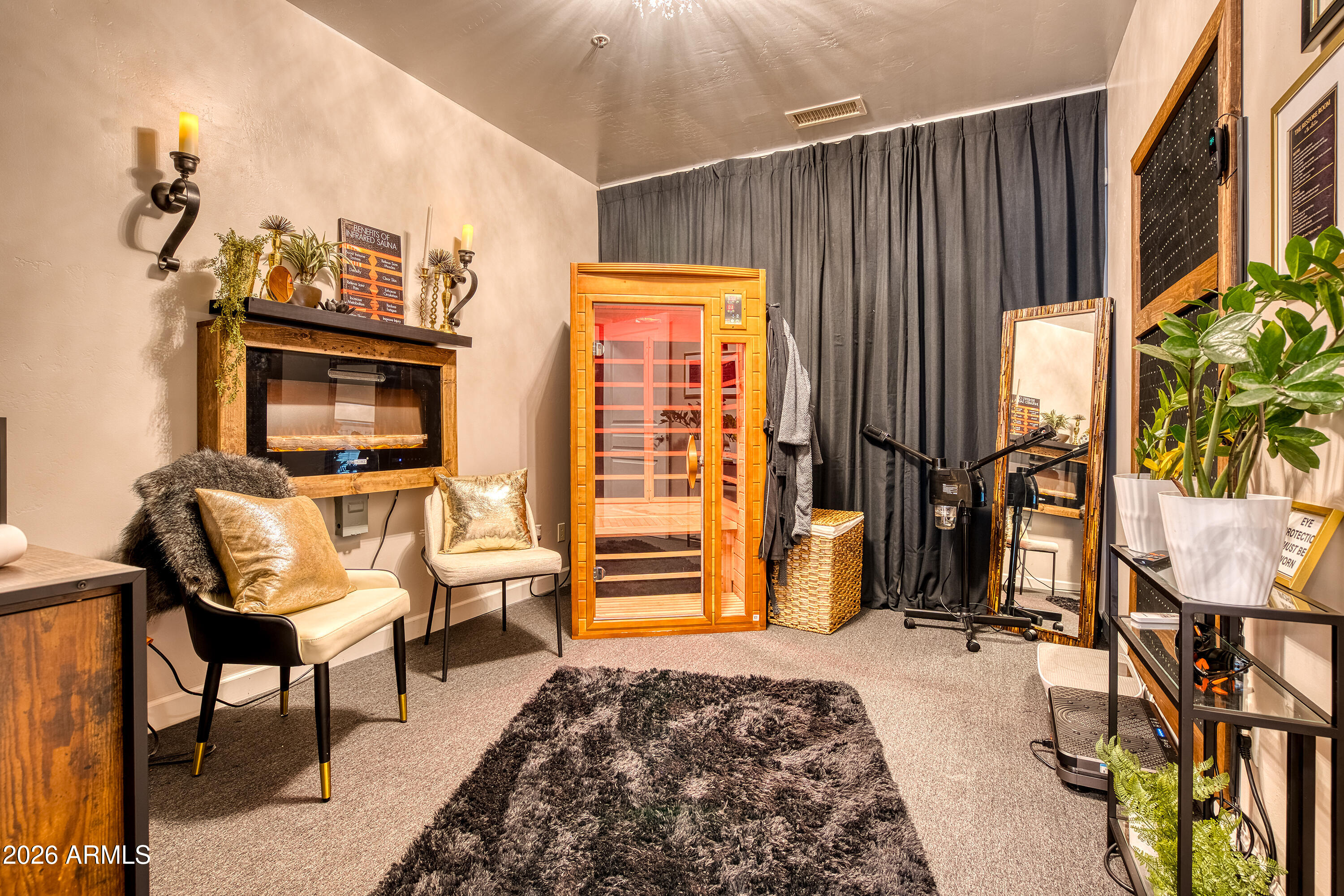 Indoor wellness room with a wooden infrared sauna, exercise equipment, mirror, and upholstered chairs.