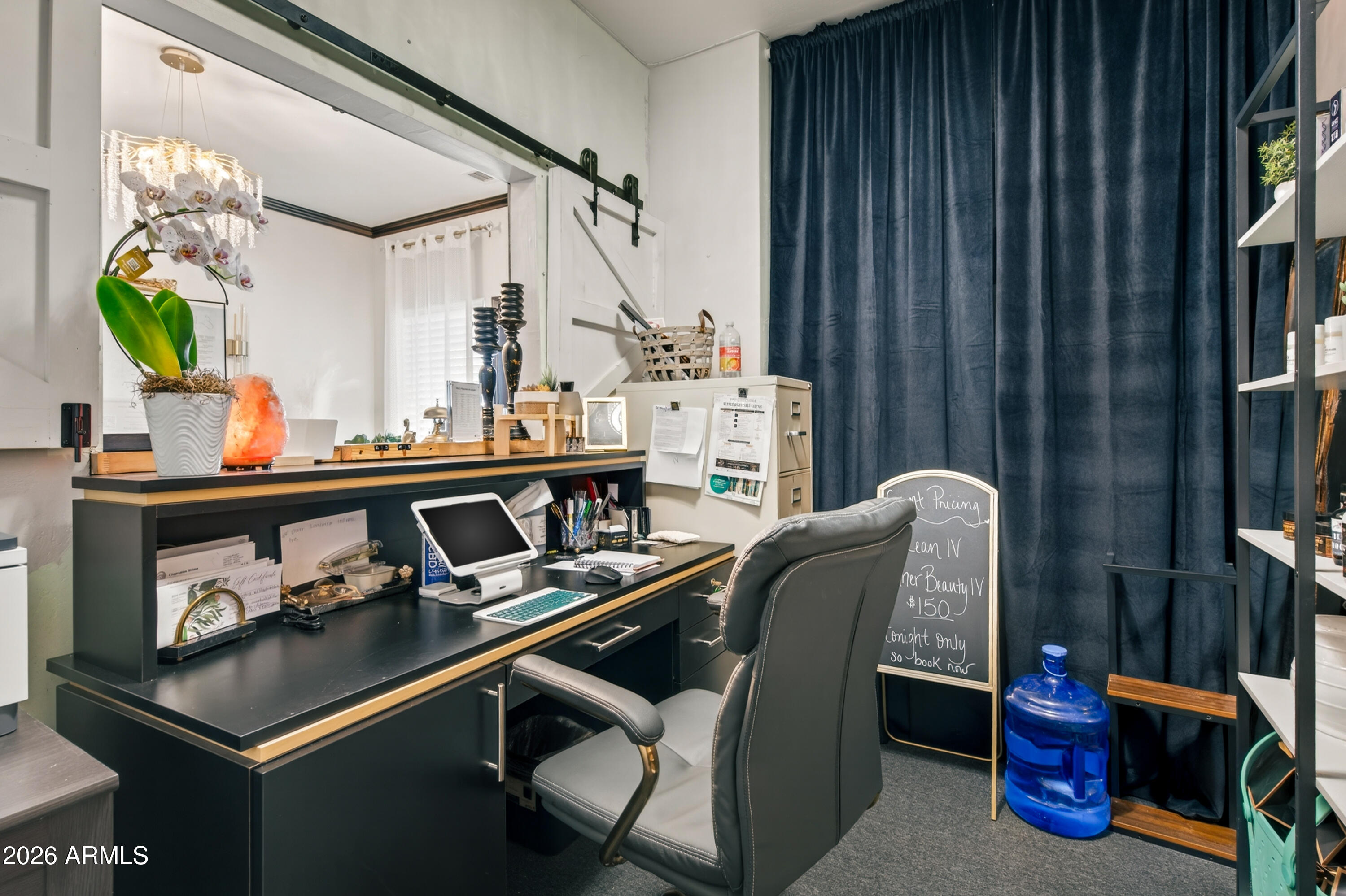 Office workspace with a black desk, gray chair, orchid, and dark blue curtains.