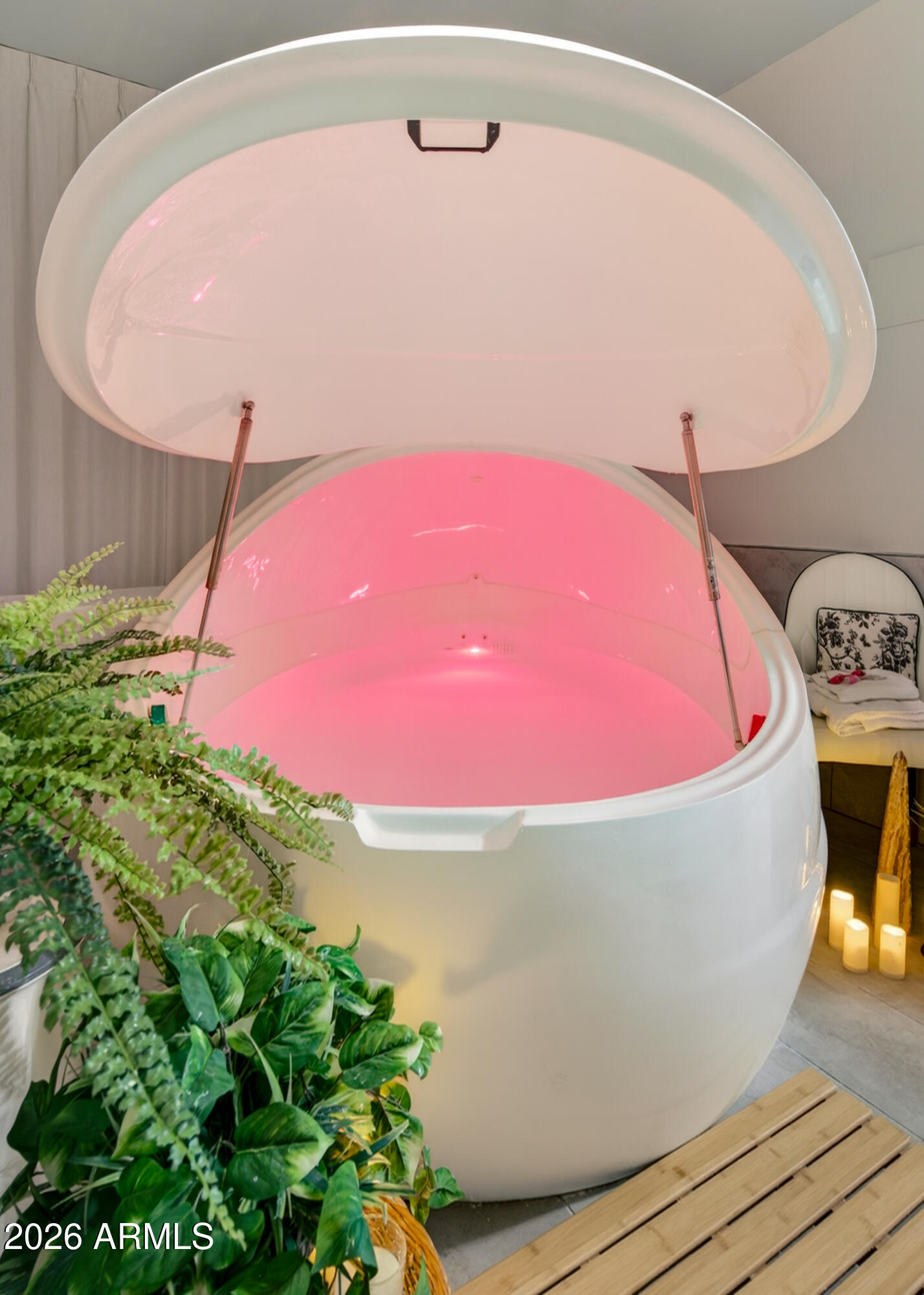 Large white soaking tub with an open domed lid and pink interior lighting.