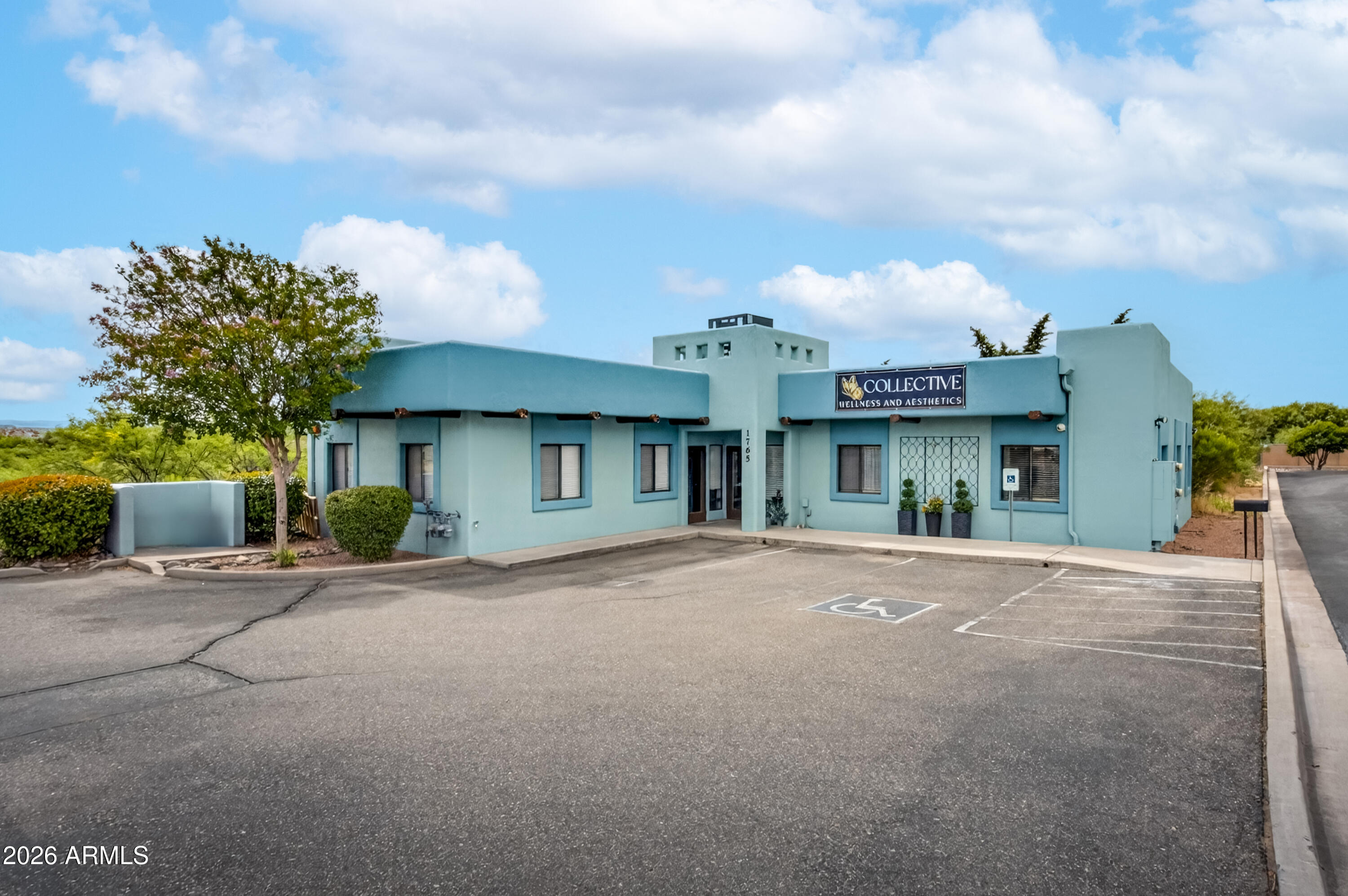 Blue-green wellness and aesthetics building with a flat roof and accessible parking.