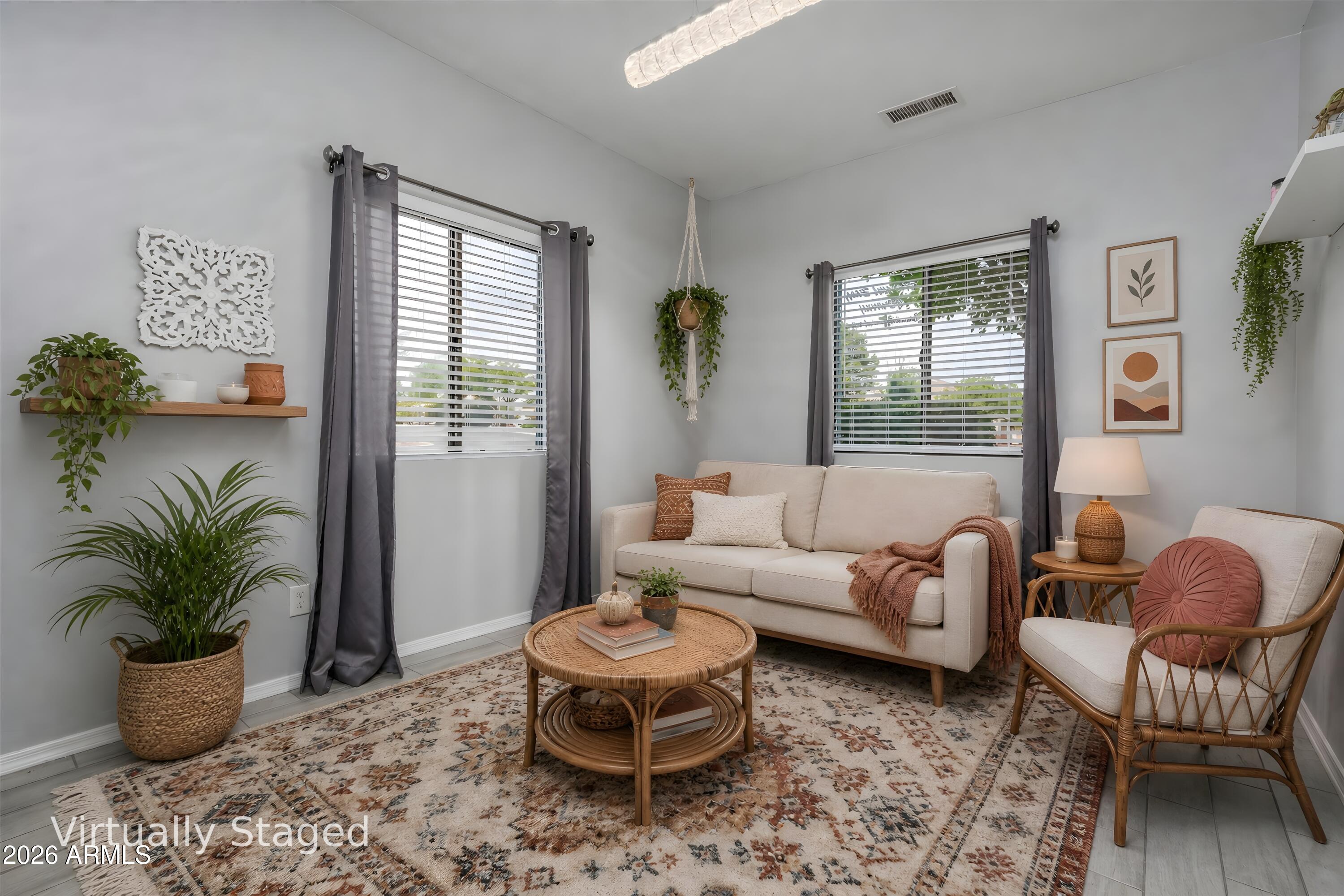 Virtually staged living room with a cream sofa, wicker chair, rattan coffee table, and patterned rug.