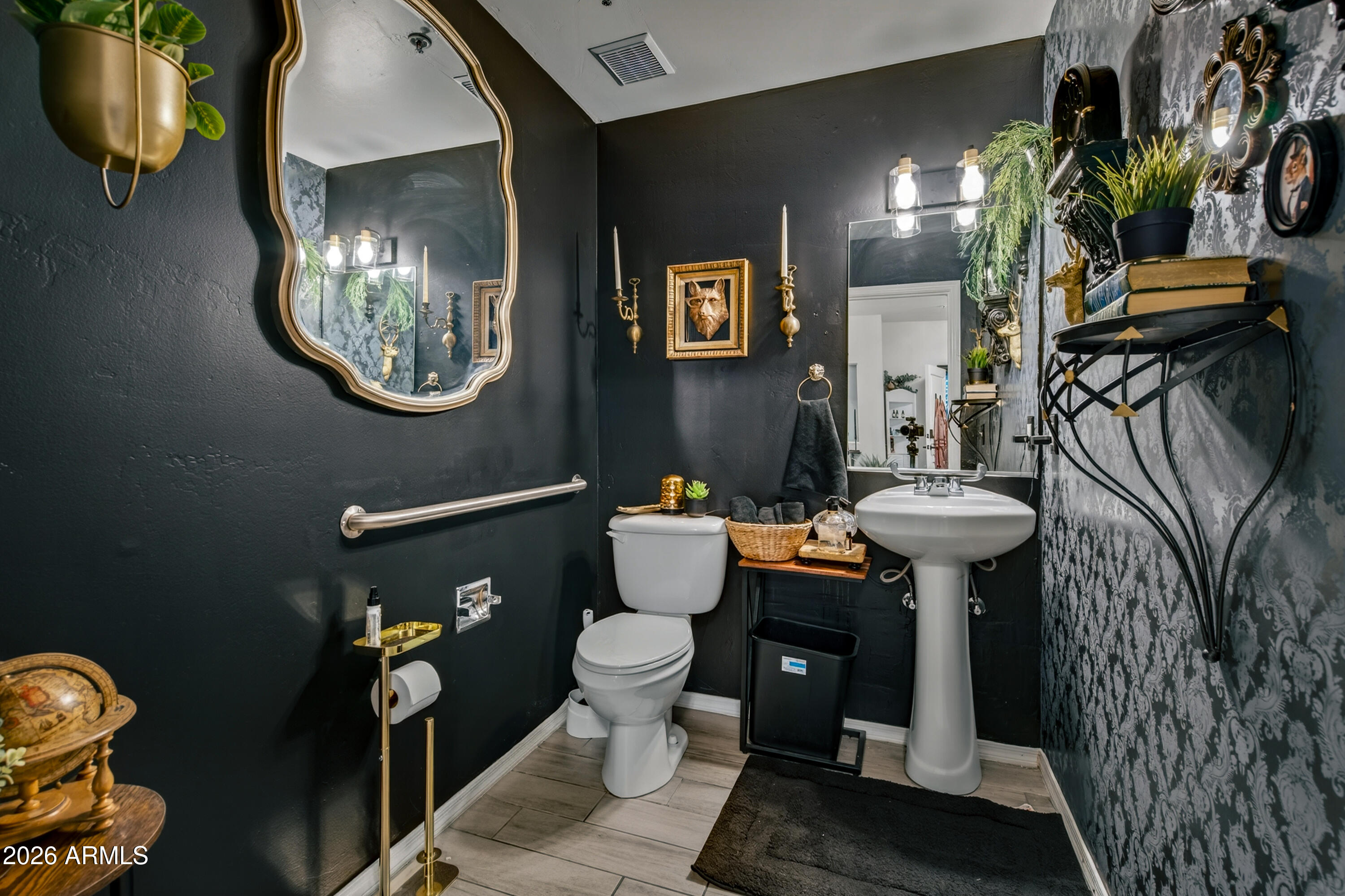 Bathroom with charcoal walls, patterned wallpaper, a pedestal sink, and an ornate mirror.