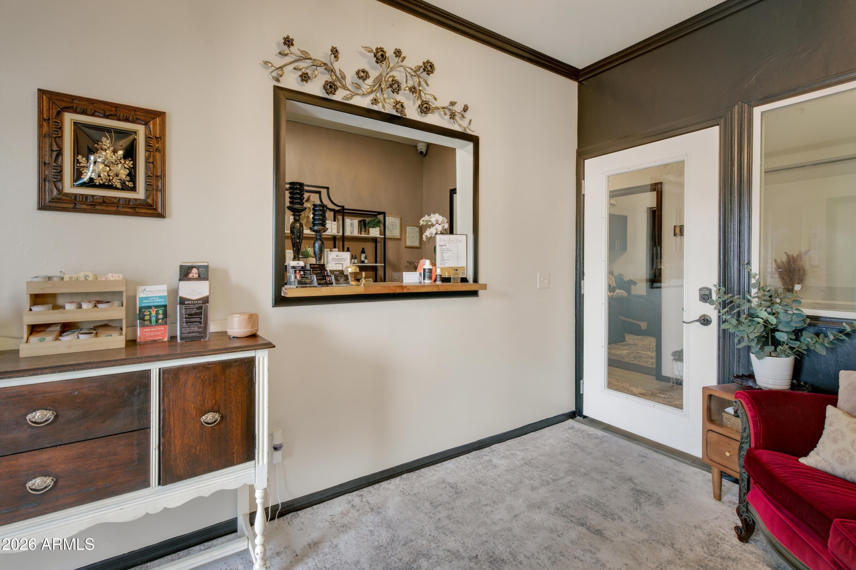 Furnished reception area with a pass-through counter, dark wood cabinet, and red upholstered chair.