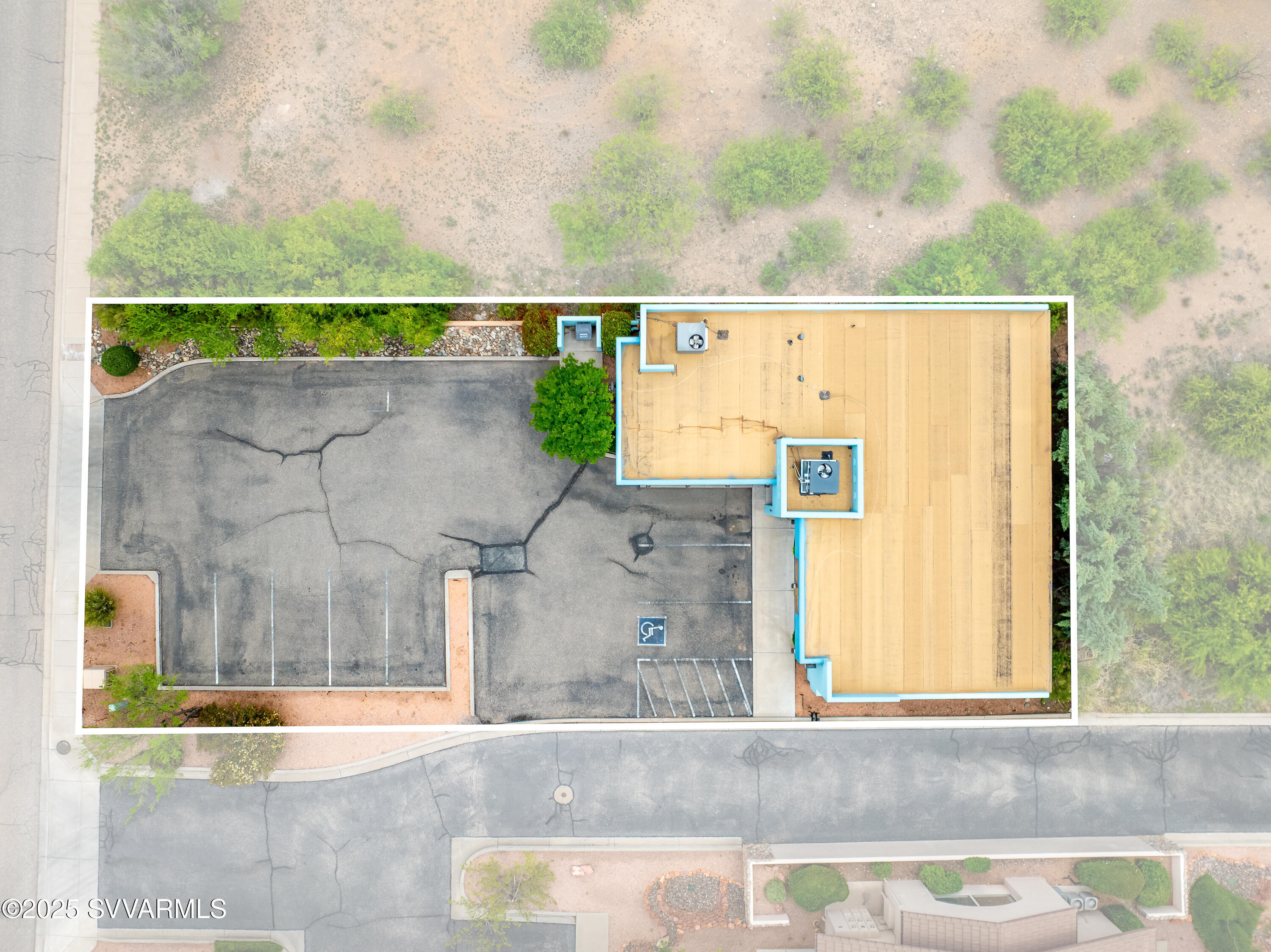 Aerial view of a commercial building and parking lot, with a tan roof and marked accessible spaces.