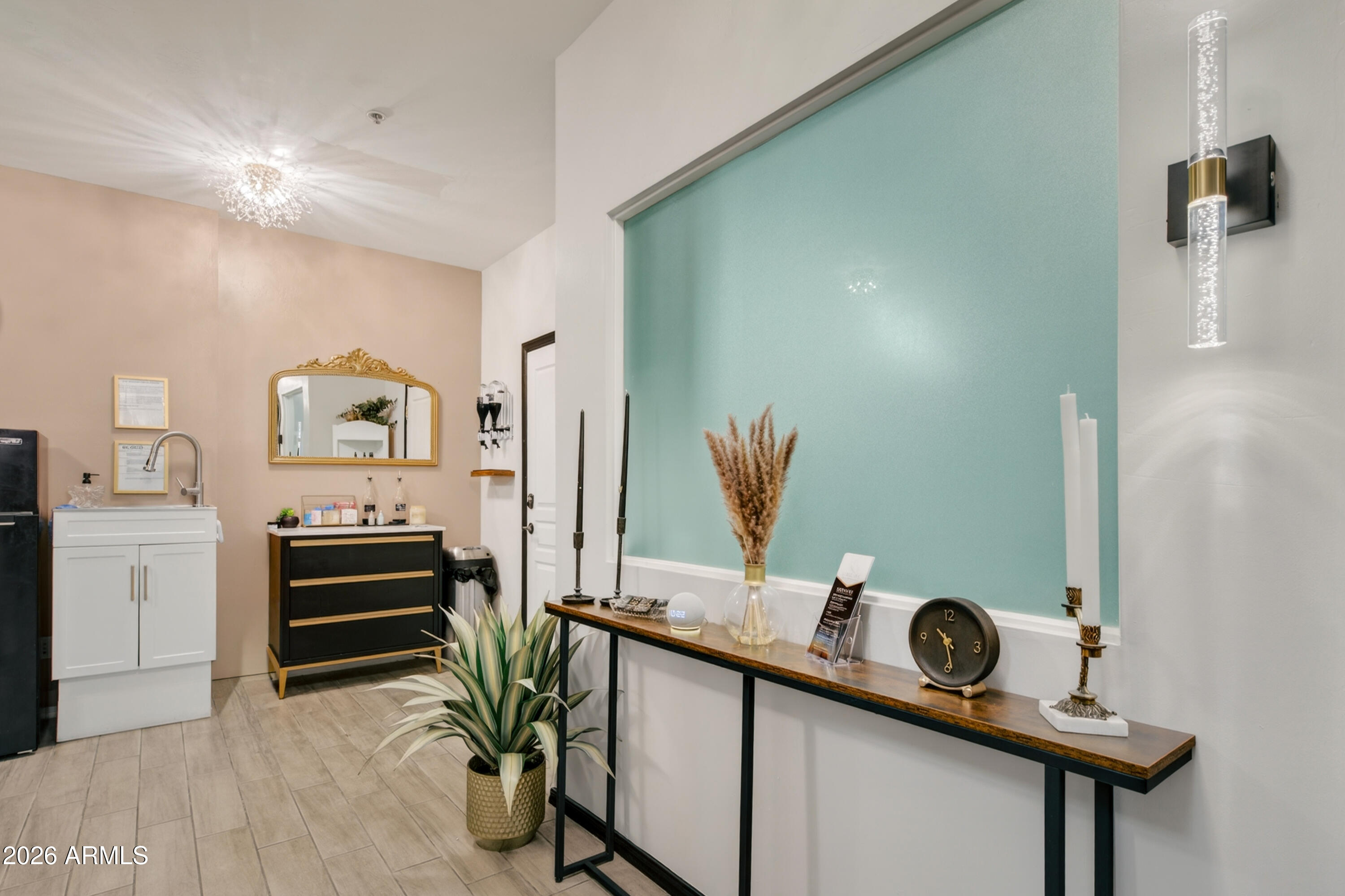 Furnished interior with a turquoise accent wall, long console table, sink cabinet, and black-and-gold dresser.