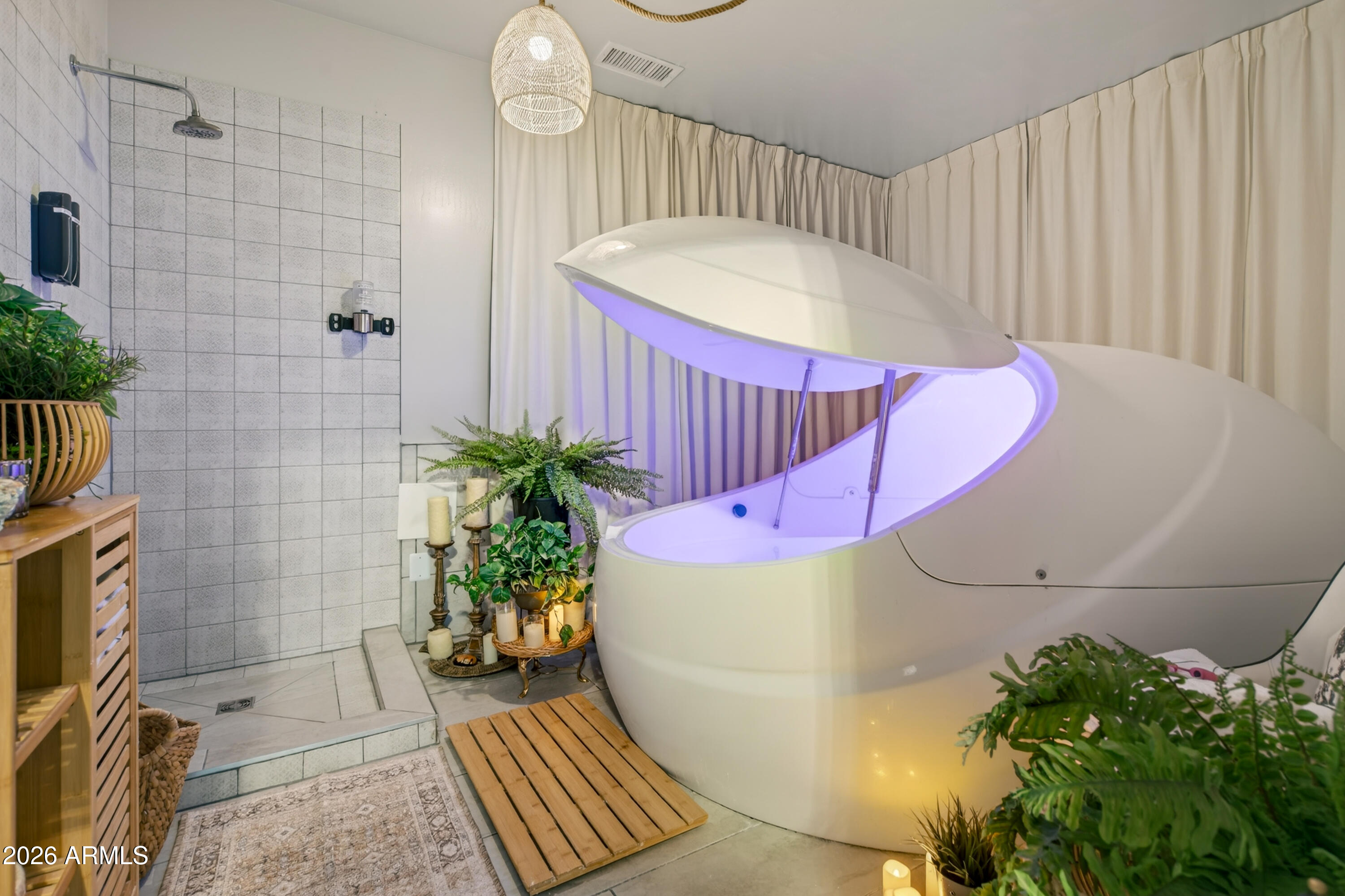 Spa bathroom with a purple-lit flotation pod beside a tiled walk-in shower.