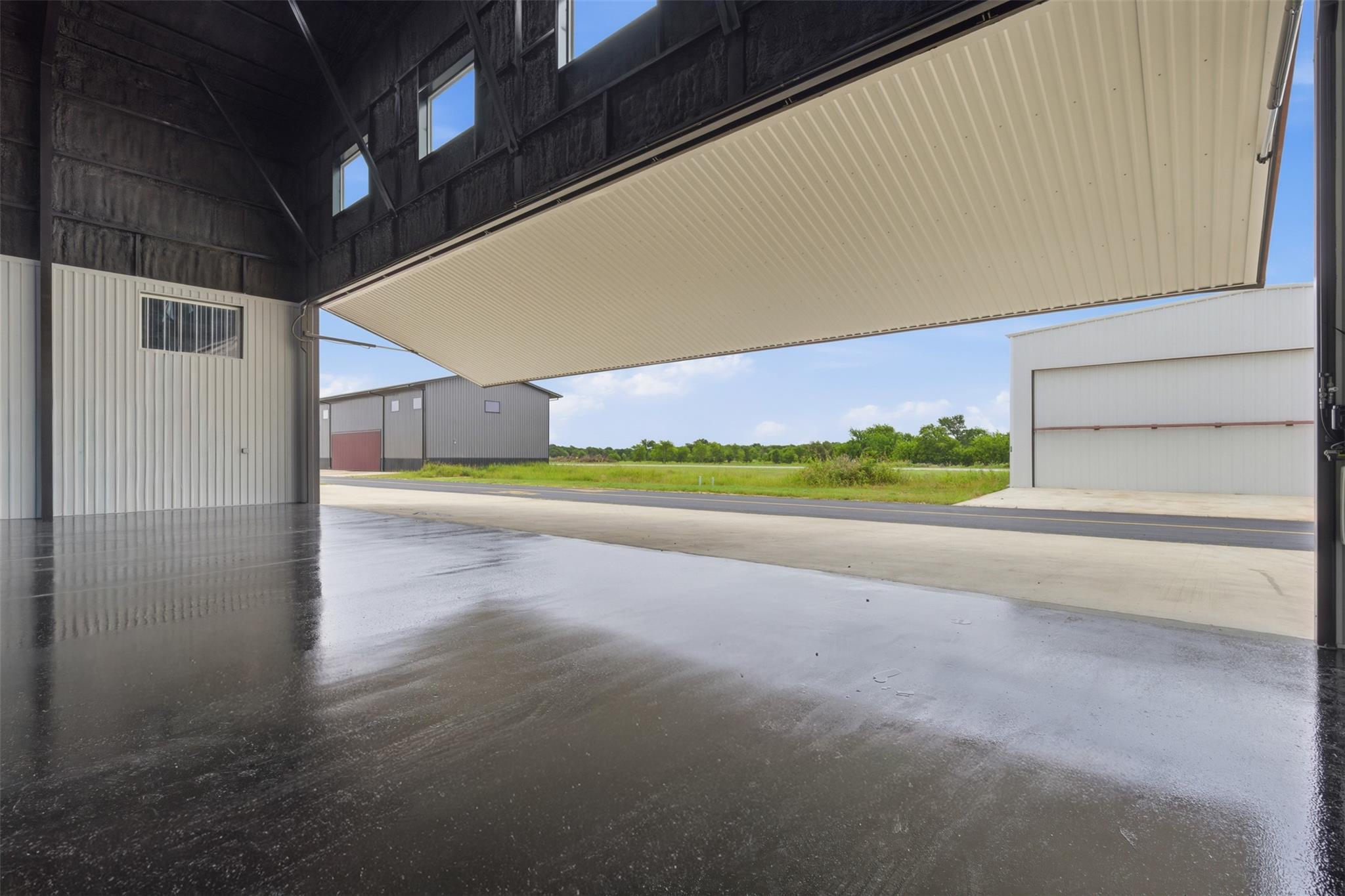 Empty aircraft hangar with polished concrete floor and a large open overhead door.