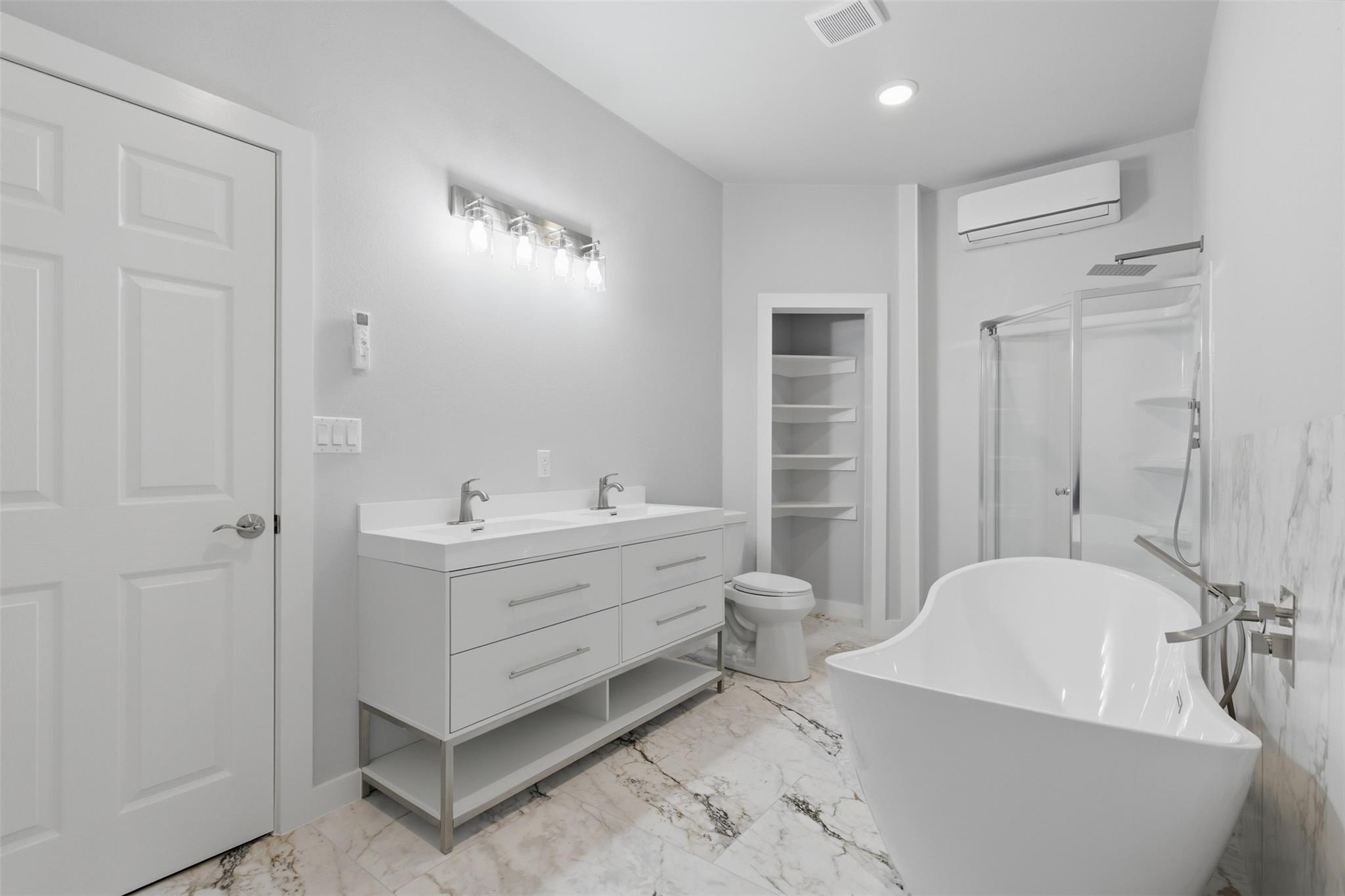 Modern bathroom with a double vanity, freestanding tub, and glass-enclosed shower.