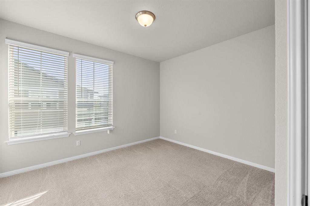 Empty carpeted bedroom with two windows and a ceiling light.