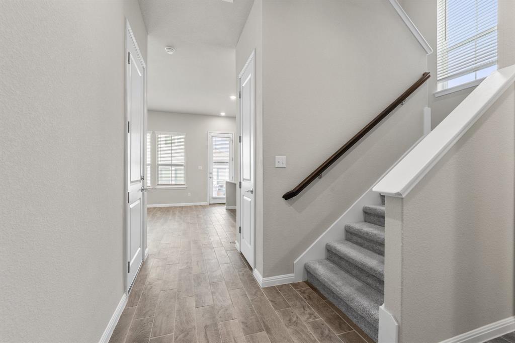 Entry hall with gray tile flooring and a carpeted staircase leading upstairs.