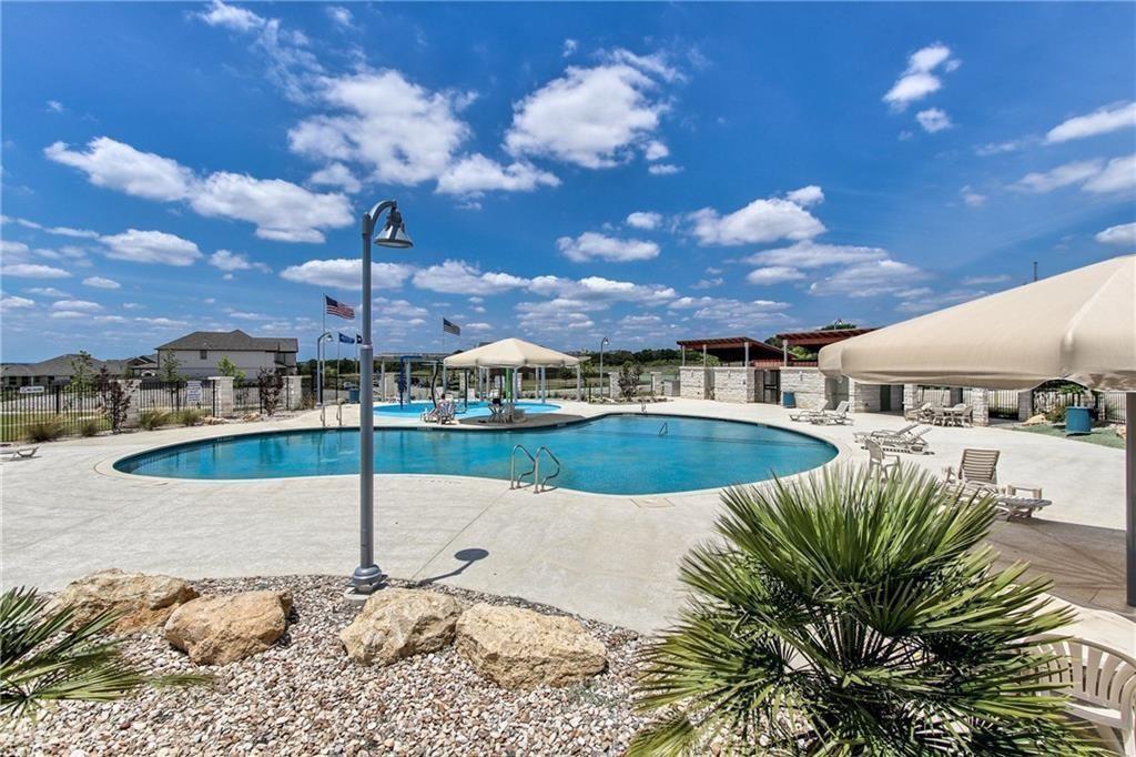 Community pool with curved water, shaded lounge chairs, and landscaped rock beds.
