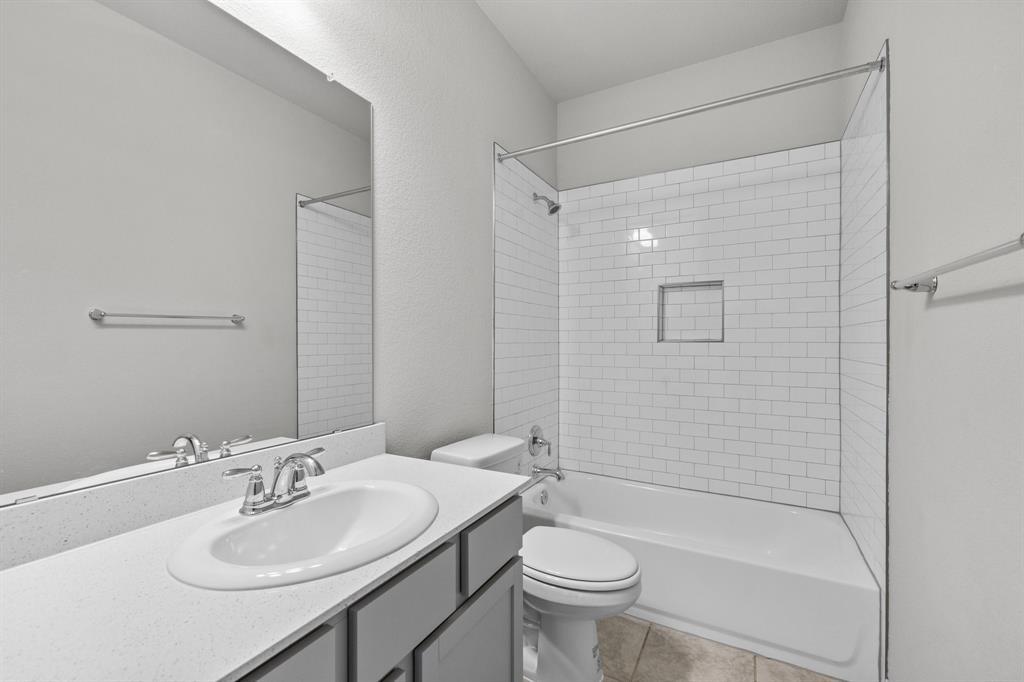 Bathroom with a white vanity, toilet, and subway-tile tub surround with a built-in niche.