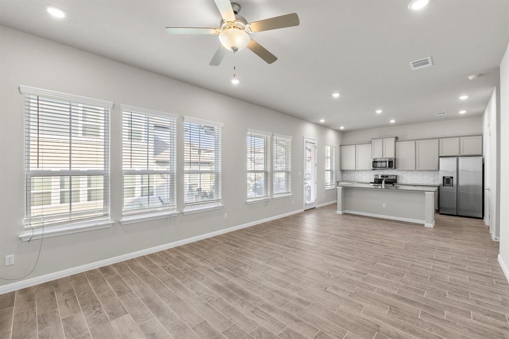 Open living area and kitchen with large windows, wood-look tile floors, and a long island.