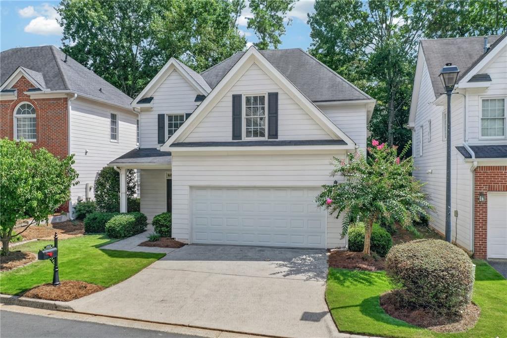 White two-story house with dark shutters, a double garage, and landscaped front yard.