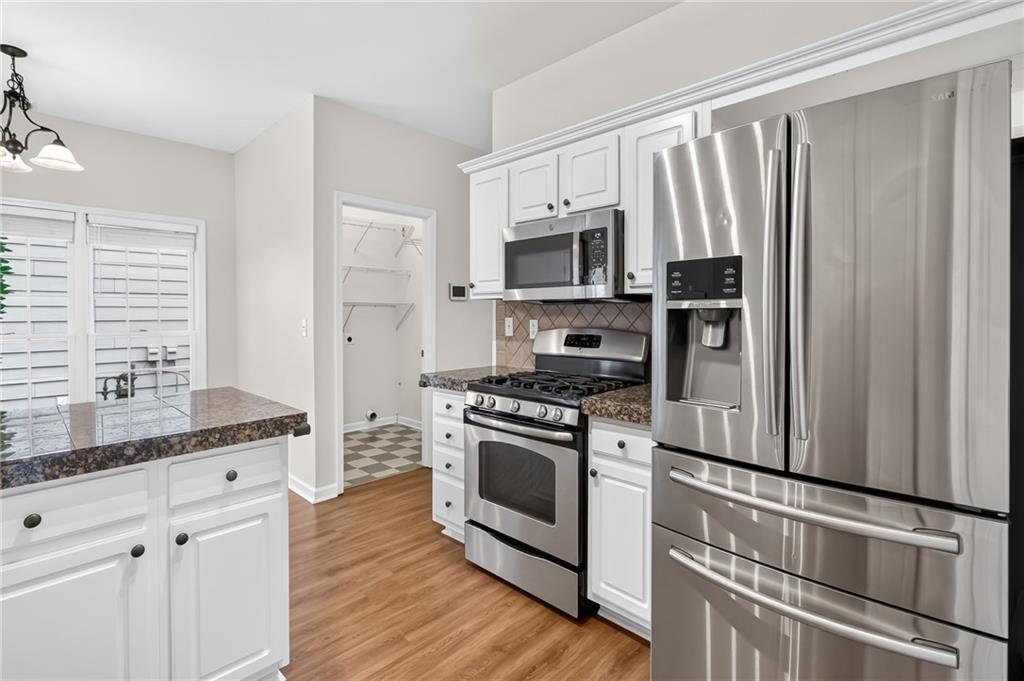 Kitchen with white cabinets, stainless steel appliances, dark counters, and a sink peninsula.