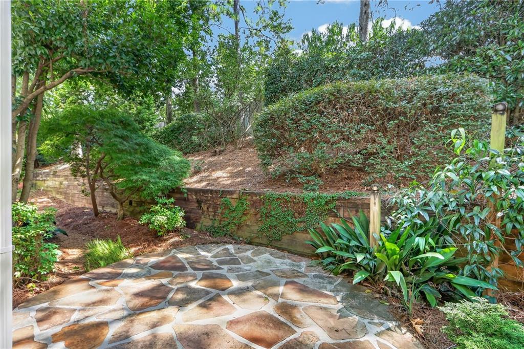Flagstone patio bordered by dense greenery and a low stone retaining wall.