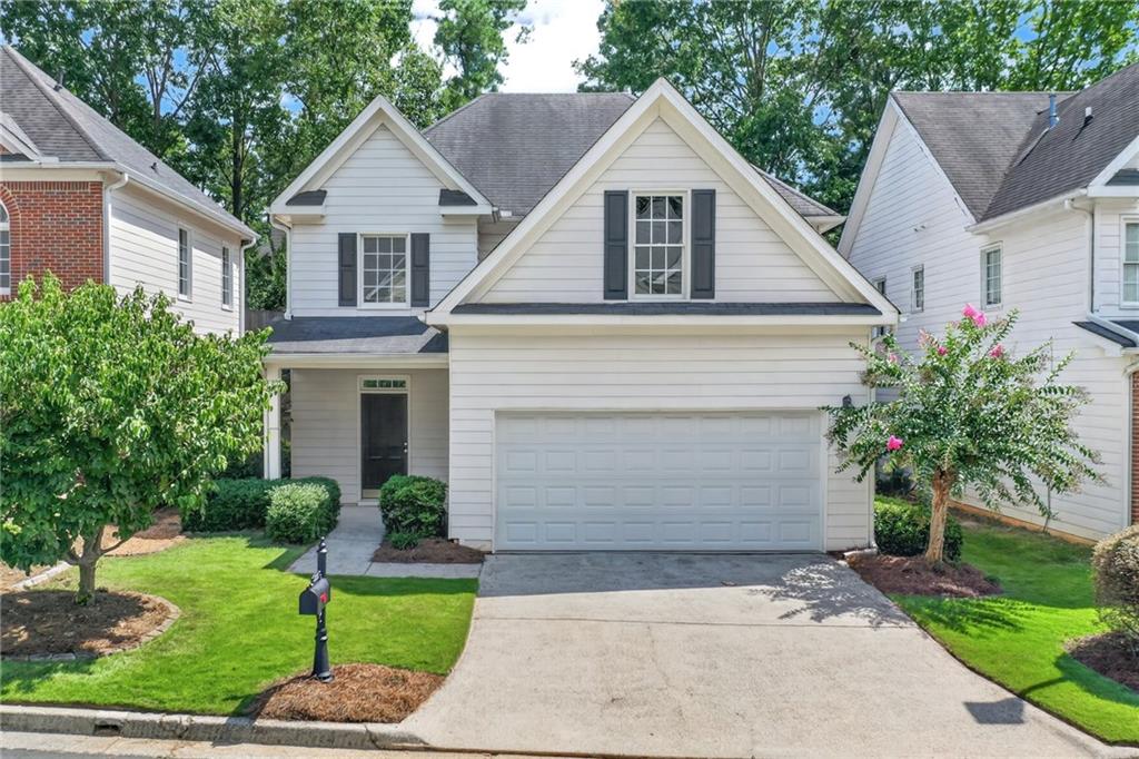 Two-story white house with dark shutters, a double garage, and a landscaped front yard.