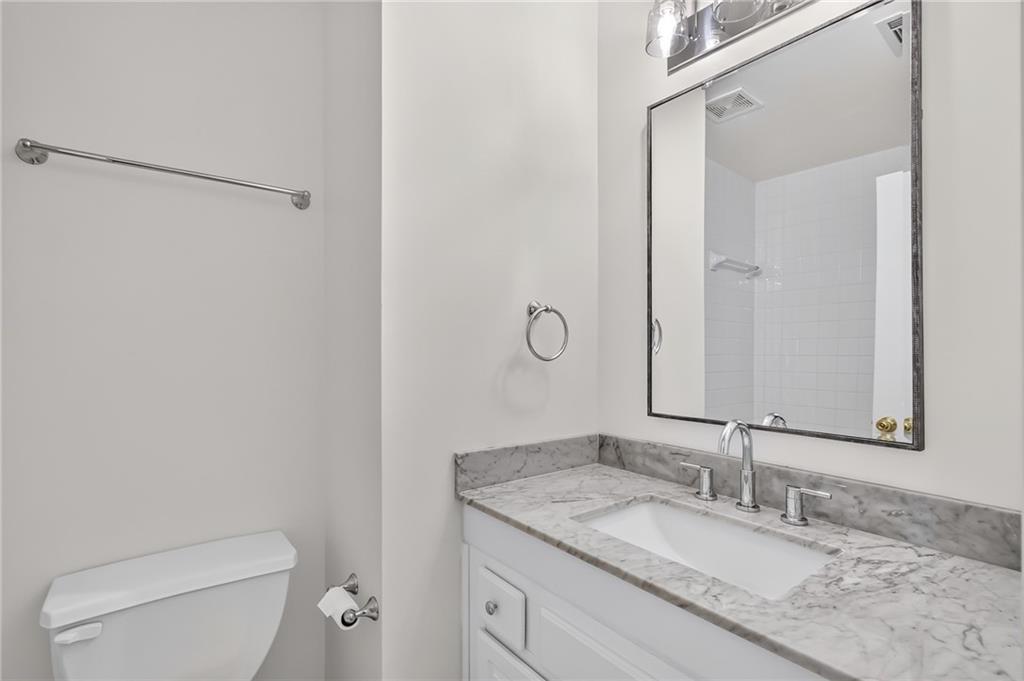 Bathroom with a gray-veined marble vanity, large mirror, and white toilet.