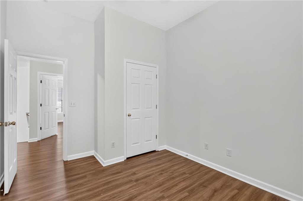 Empty room with gray walls, brown wood-look flooring, and white paneled doors.