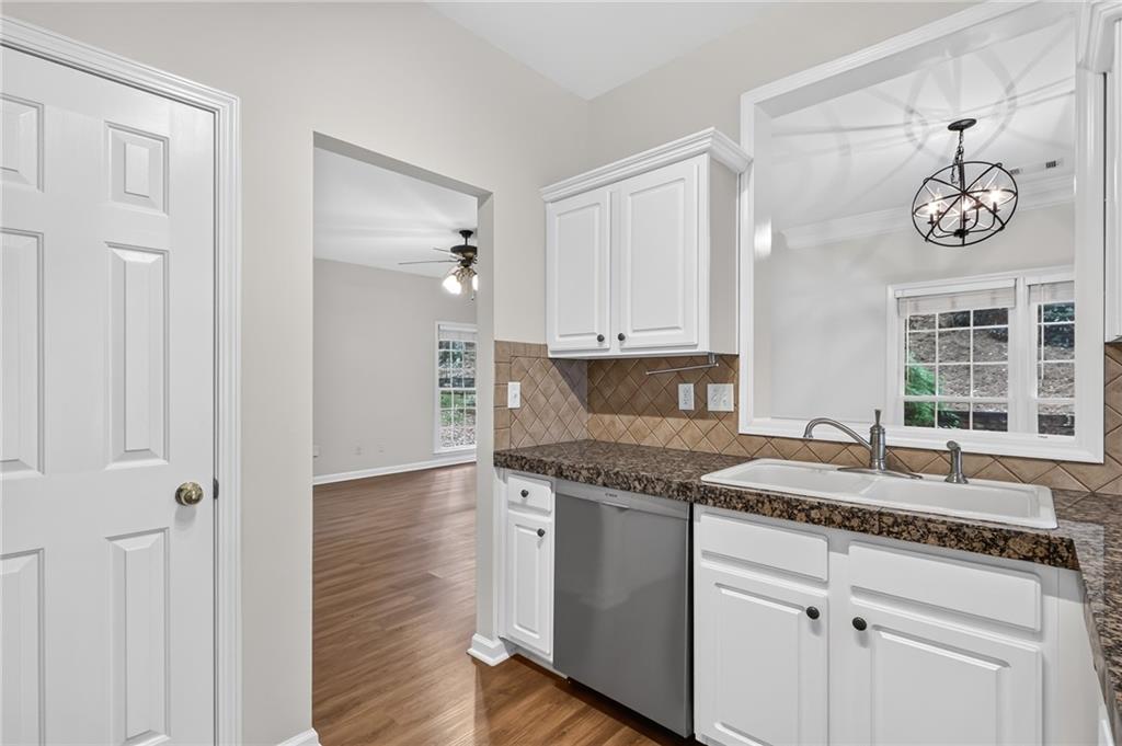 Kitchen with white cabinets, granite countertops, and a sink beneath a window.