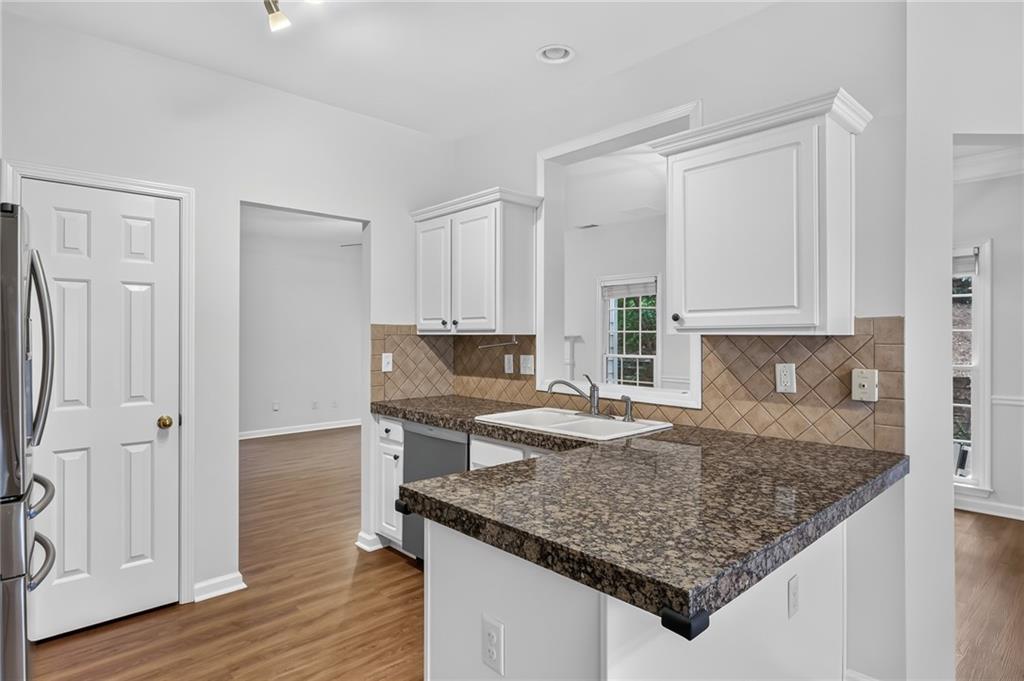 Kitchen with a dark granite peninsula, white cabinets, and tan tile backsplash.