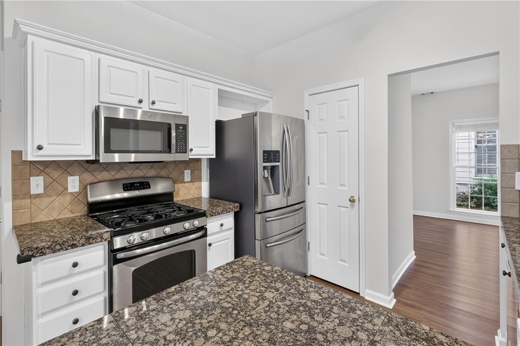 Kitchen with white cabinets, granite counters, stainless steel appliances, and a gas range.