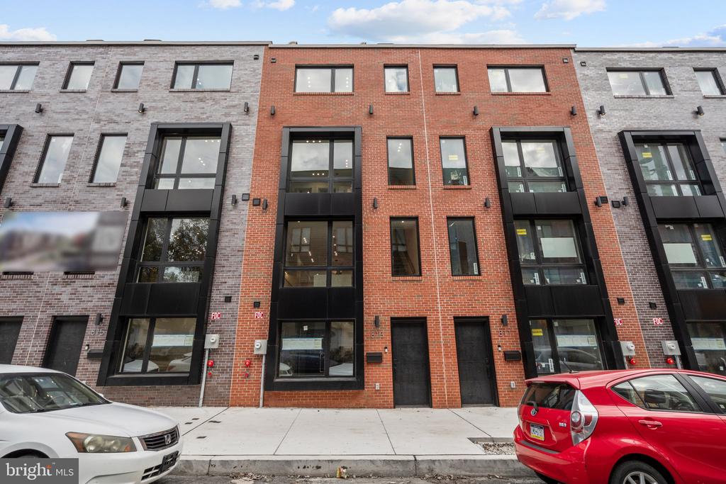 Modern attached homes with red and gray brick facades and tall black-framed windows.