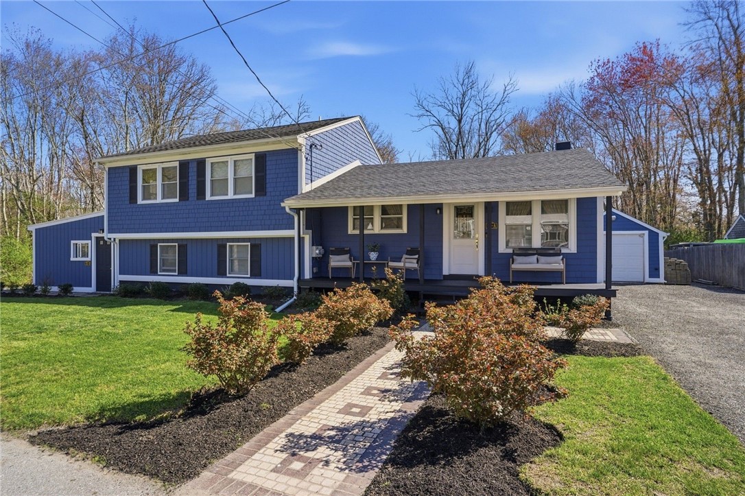 Blue split-level house with a covered porch, attached garage, and brick-paver walkway.