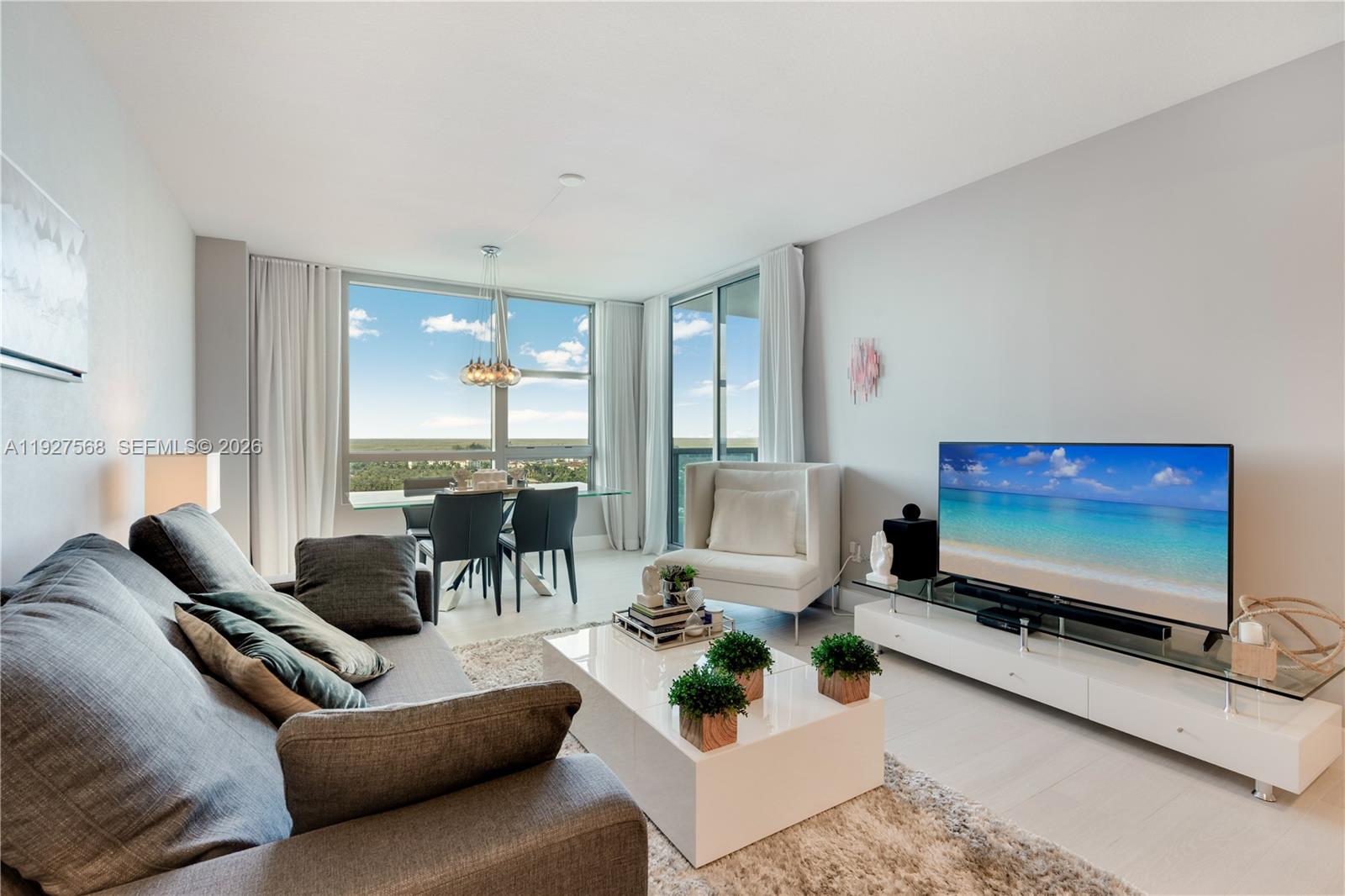 Furnished high-rise living room with floor-to-ceiling windows and a gray sectional sofa.