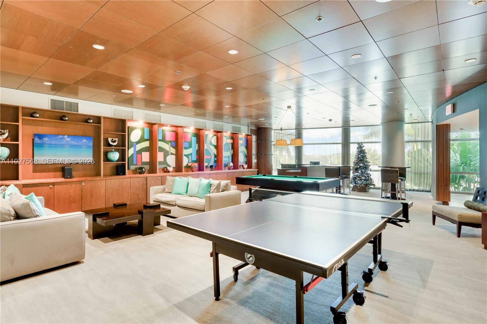 Building recreation room with ping-pong and pool tables, lounge seating, and large windows.