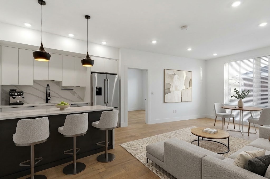Open-plan kitchen and living room with a dark island, upholstered stools, and a bright dining nook.
