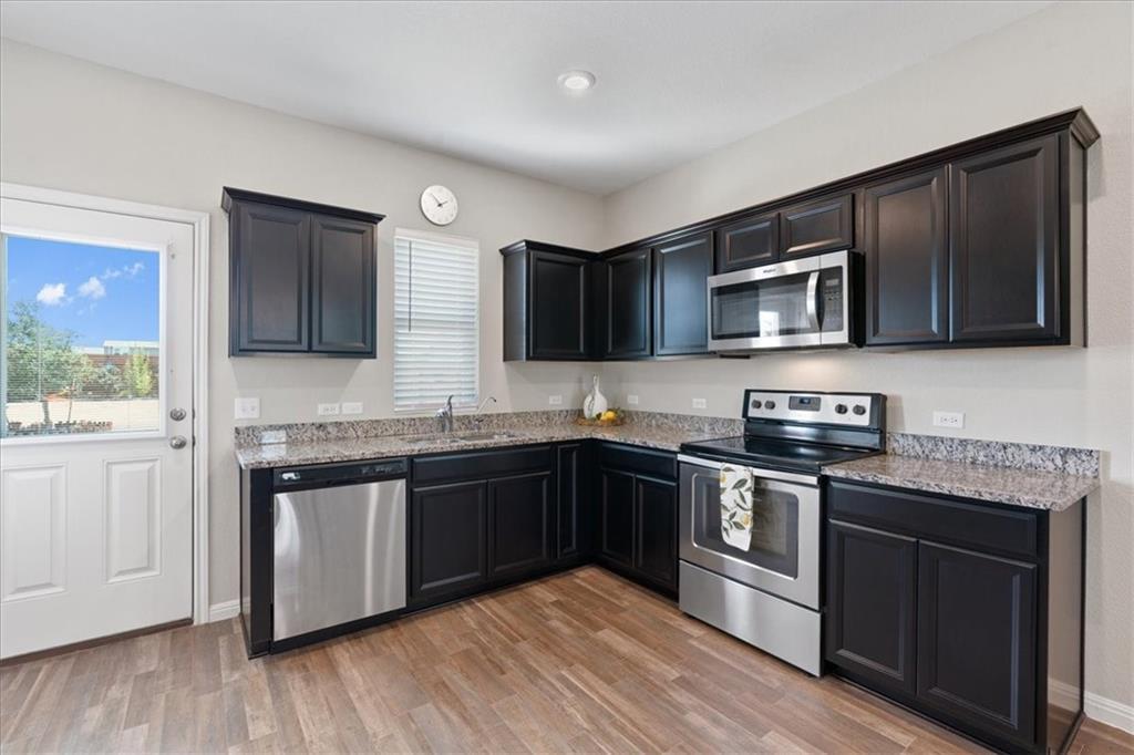 Kitchen with dark cabinets, granite counters, and stainless steel appliances.