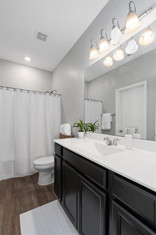 Bathroom with dark wood vanity, white countertop, illuminated mirror, and shower curtain.