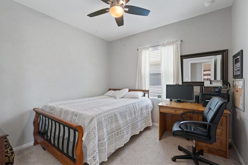 Bedroom with a wooden bed and computer desk beside a curtained window.
